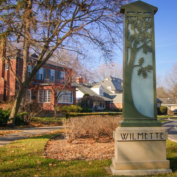 Welcome Monument for "Wilmette" With Houses in the Background and Leaves on the Ground